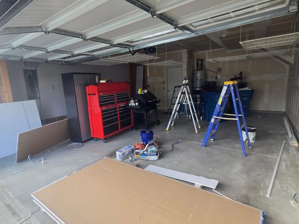 Garage before epoxy floor coating - bare concrete mid-renovation with construction materials